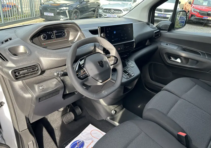 Intérieur du Peugeot Partner Fourgon 2025, vue côté conducteur, tableau de bord moderne avec écran tactile et volant multifonction.
