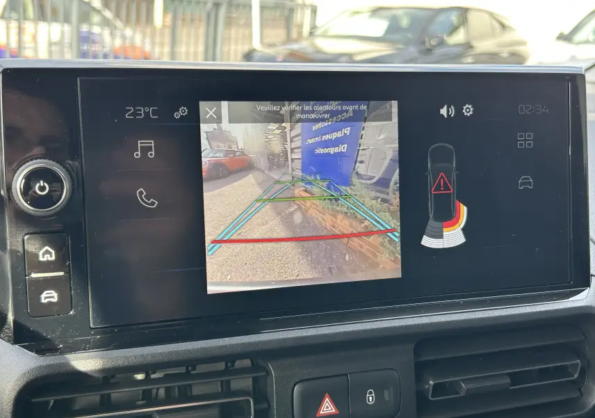Écran multimédia du Peugeot Partner Fourgon blanc montrant la caméra de recul et les capteurs d'aide au stationnement.