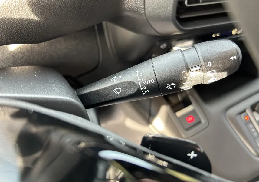 Gros plan sur la commande d'essuie-glace droite du Peugeot Partner Fourgon 2025 avec palettes au volant et tableau de bord noir.