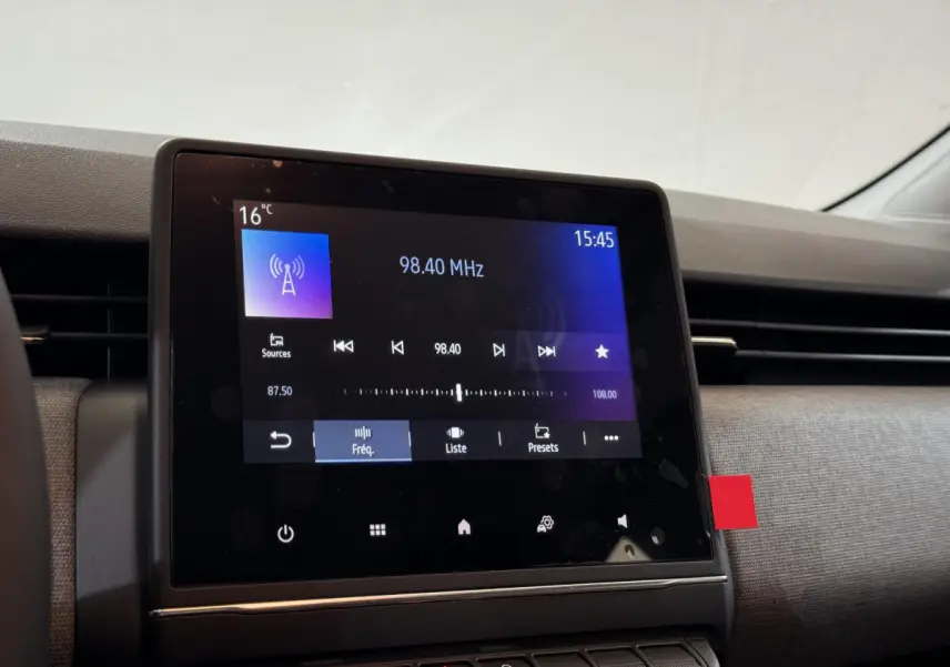 Écran tactile central affichant la radio dans l'habitacle d'une Renault Clio gris clair, vue de face.