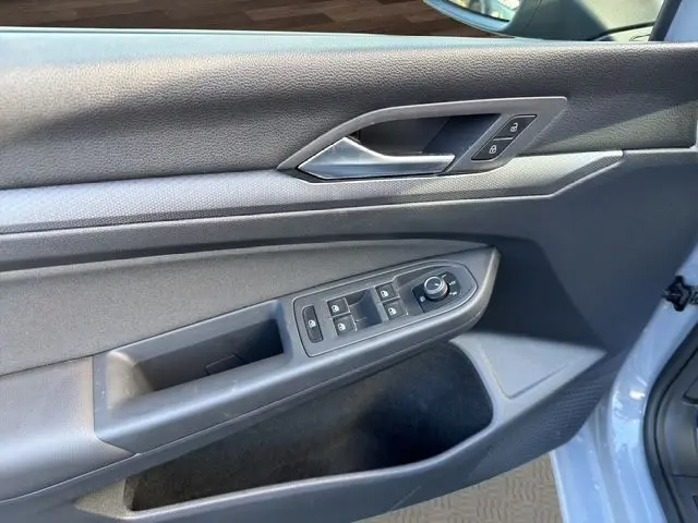 Vue côté intérieur de la porte avant gauche gris lunaire de la Volkswagen Golf VIII avec commandes de vitres et rétroviseurs.