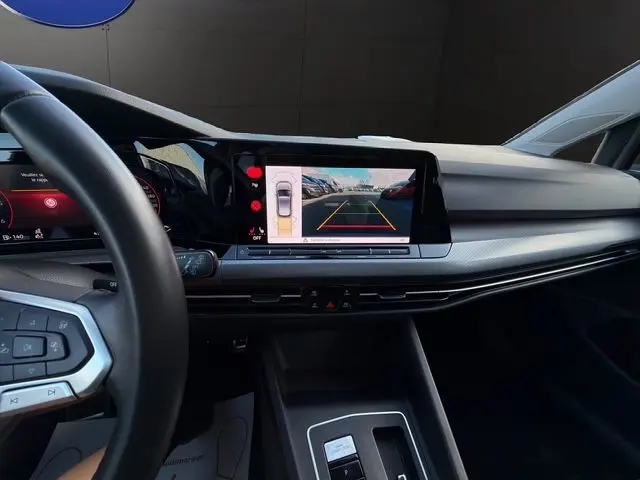 Vue intérieure du tableau de bord de la Volkswagen Golf VIII gris lunaire, avec écran tactile affichant la caméra de recul.