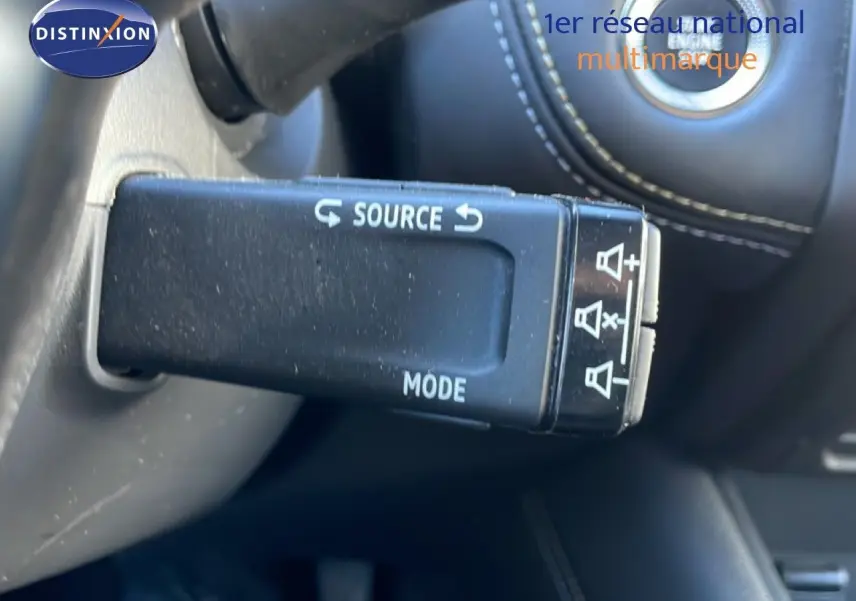 Gros plan sur la commande au volant gauche de la Renault Symbioz bleu Iron Metal, avec bouton source et mode visibles.