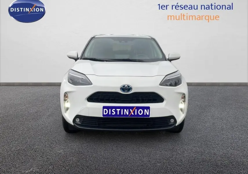 Vue frontale d'une Toyota Yaris Cross Hybrid blanche de 2024 avec phares allumés et calandre noire.