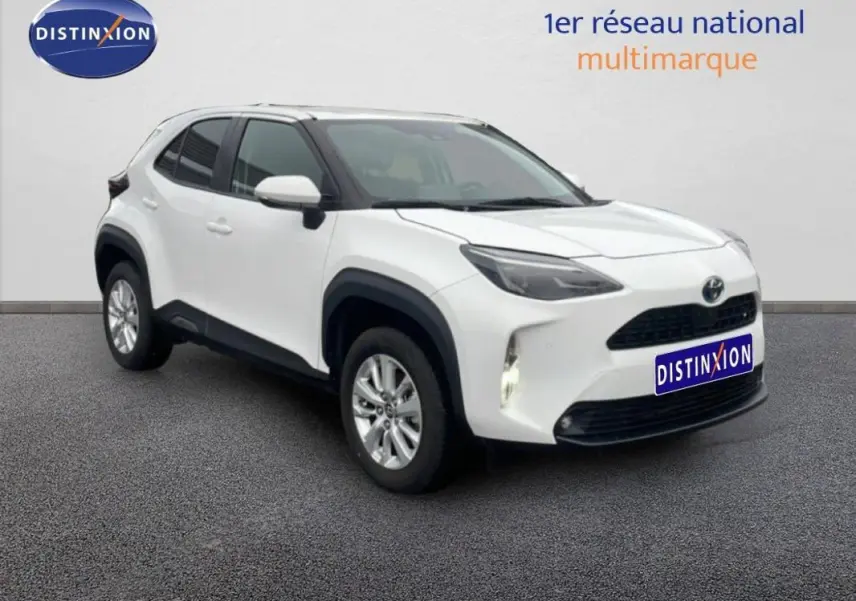 Toyota Yaris Cross Hybrid blanc vue 3/4 avant droit avec jantes aluminium et phares allumés.