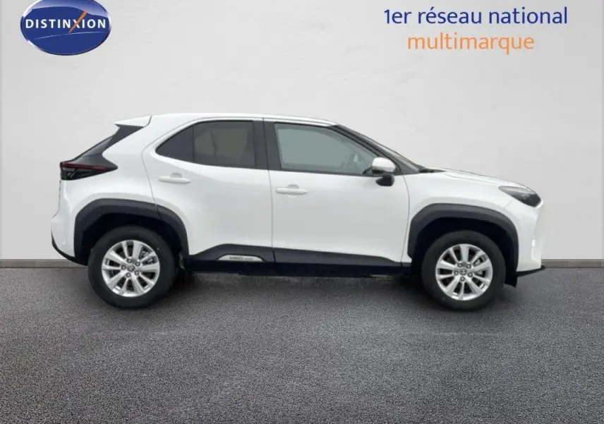 Profil droit d'un Toyota Yaris Cross blanc 2024 hybride avec jantes aluminium 16 pouces et protections noires.