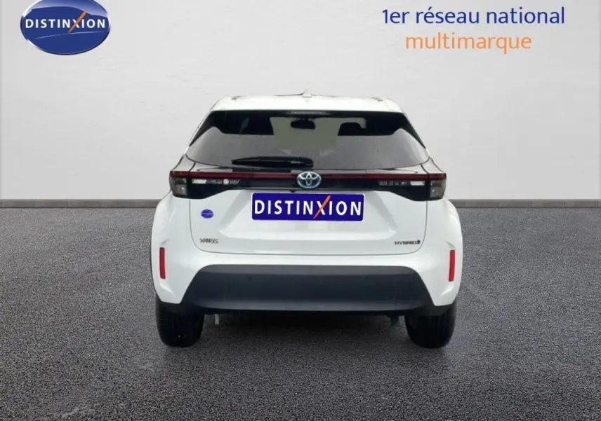 Vue arrière d'une Toyota Yaris Cross Hybrid blanche de 2024, avec feux arrière noirs et logo Toyota visible.
