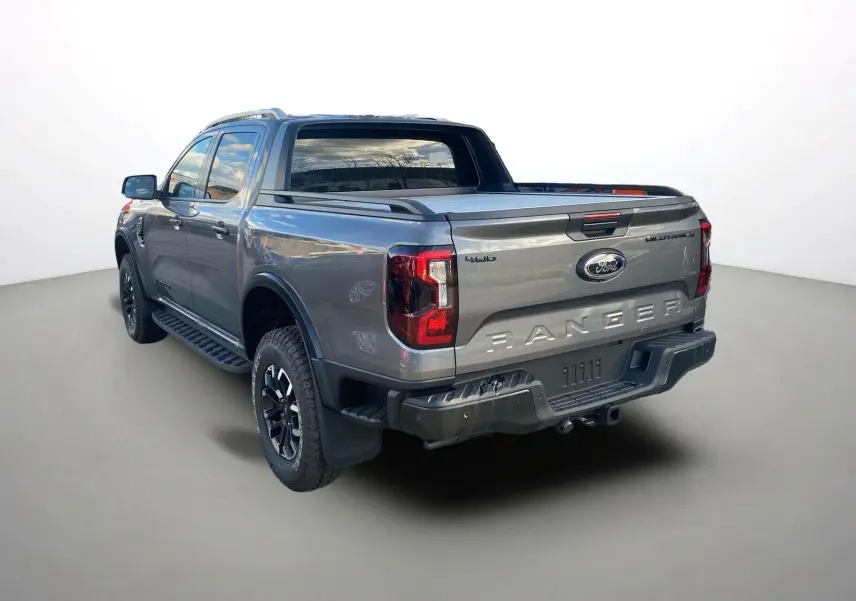 Ford Ranger 2026 gris carbone vu 3/4 arrière droit avec rideau de benne et jantes noires distinctives.