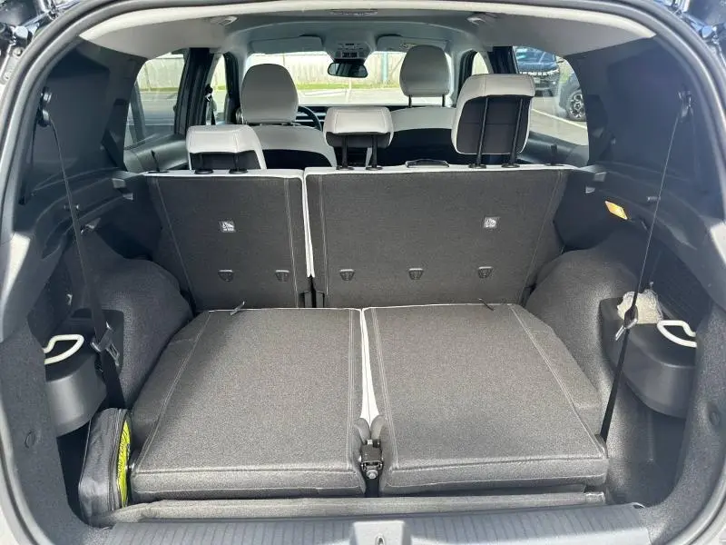 Vue arrière du coffre du Citroën C3 Aircross gris Mercury avec sièges arrière rabattus et banquette partiellement relevée.
