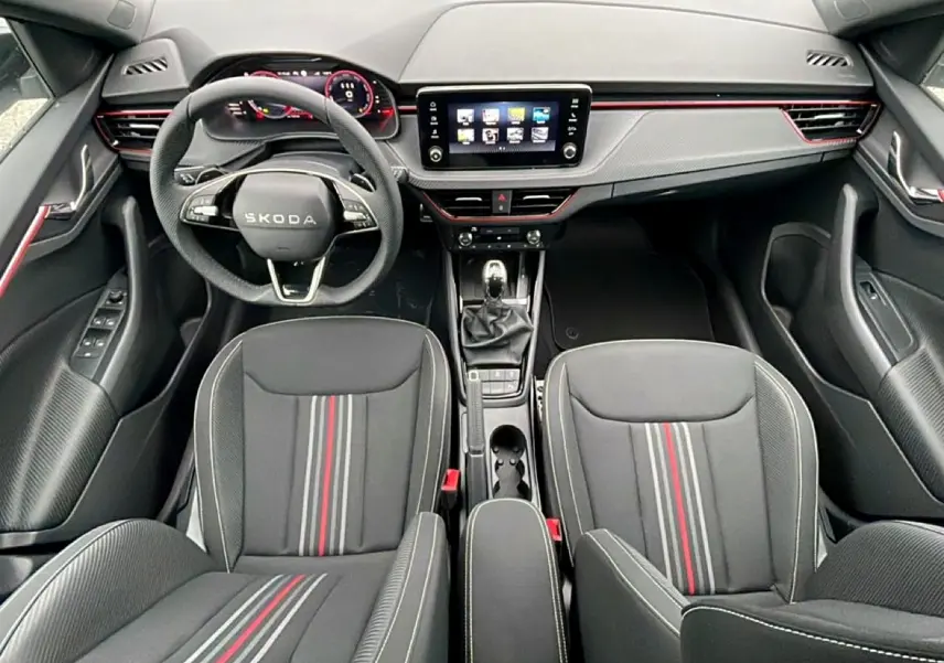 Vue intérieure avant du Skoda Kamiq 2026 Monte Carlo, sièges noirs avec bandes rouges et tableau de bord moderne avec écran tactile.