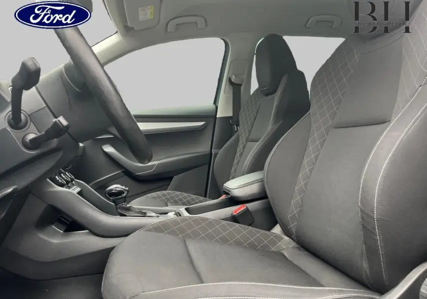 Vue intérieure côté conducteur du Skoda Karoq 1.6 TDI 2020, sièges tissu gris avec surpiqûres croisées.