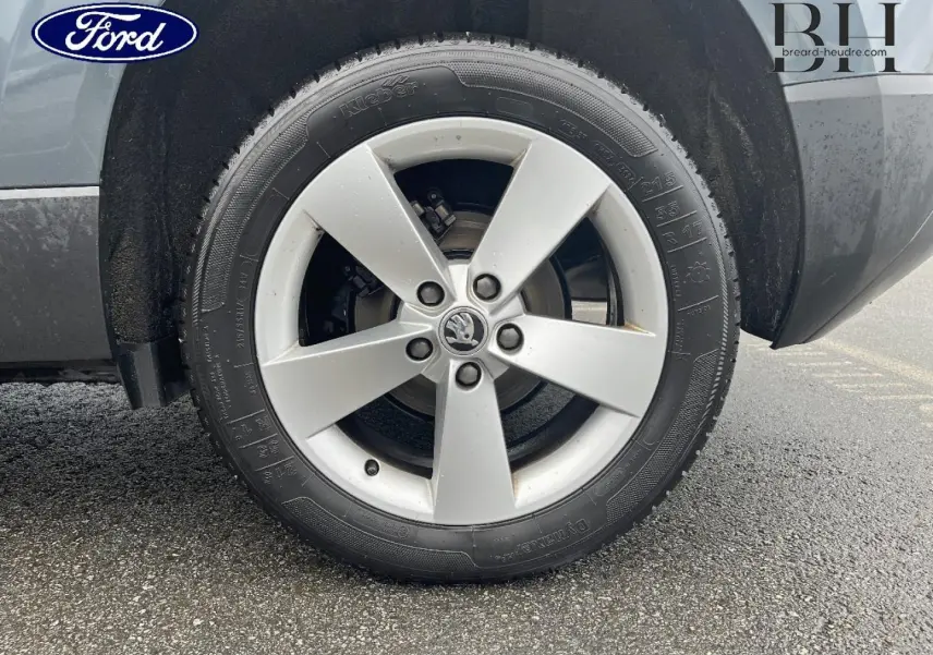 Gros plan sur la roue avant gauche d'un Skoda Karoq gris Business avec jante alliage cinq branches.