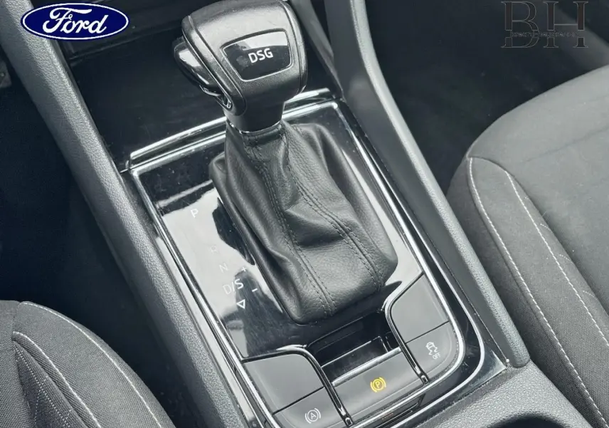 Gros plan sur le levier de vitesses DSG noir et cuir dans l'habitacle d'un Skoda Karoq gris Business, console centrale visible.