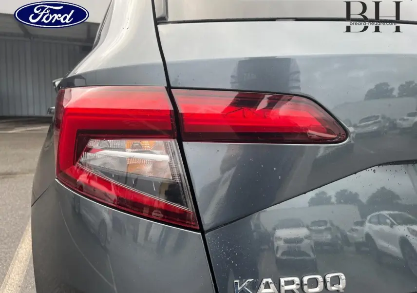 Gros plan sur le feu arrière gauche d’un Skoda Karoq gris Business, soulignant la finition et les lignes du coffre.