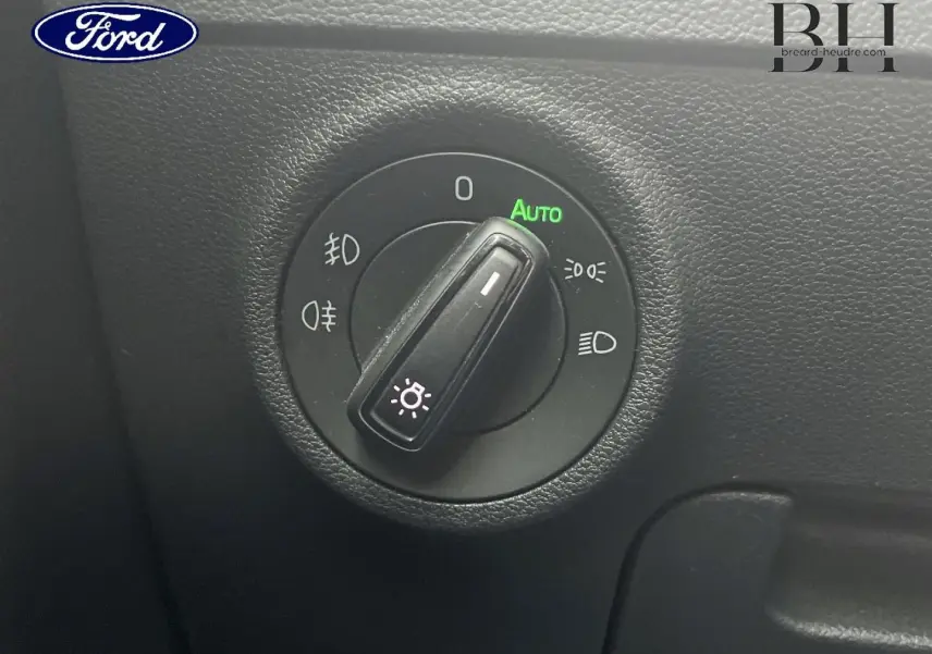 Gros plan sur le sélecteur de feux d’un Skoda Karoq gris Business, avec mode automatique activé.