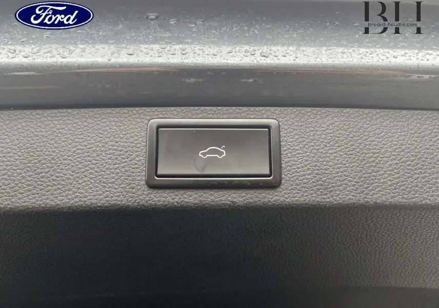 Bouton d'ouverture électrique du coffre sur la plage arrière d'un Skoda Karoq gris Business, vue rapprochée.