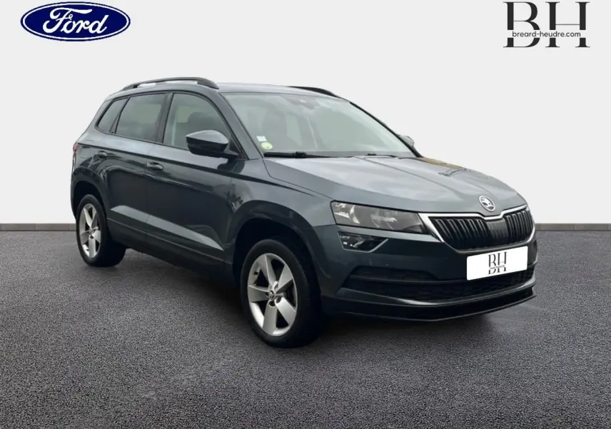SUV Skoda Karoq gris Business vu en 3/4 avant droit, avec jantes alliage et calandre noire distinctive.