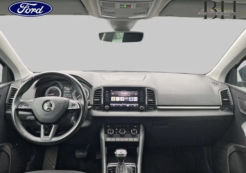 Vue intérieure avant du Skoda Karoq 2020, tableau de bord gris avec écran tactile et volant multifonction cuir.