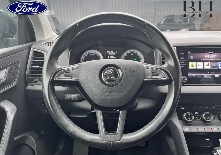 Vue intérieure centrée sur le volant cuir noir d'un Skoda Karoq 2020 avec tableau de bord et écran tactile visibles.