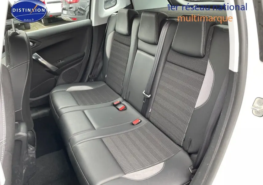 Vue intérieure arrière côté droit du Peugeot 2008 blanc nacré, montrant les sièges en cuir noir avec surpiqûres grises.
