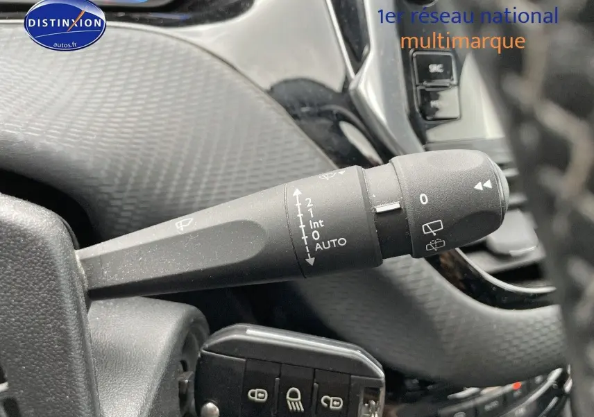 Gros plan sur la commande d'essuie-glace à gauche du volant dans l'habitacle d'un Peugeot 2008 blanc nacré de 2015.