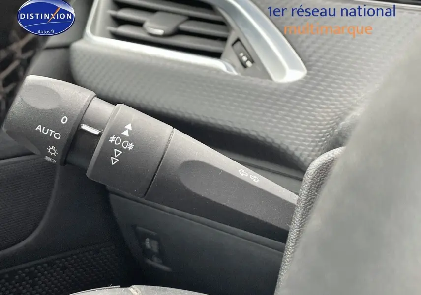 Gros plan sur la manette des feux et clignotants du tableau de bord d'un Peugeot 2008 blanc nacré de 2015.