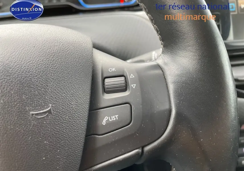 Gros plan sur les commandes au volant noir du Peugeot 2008 blanc nacré, mettant en valeur les boutons de gestion d'appel et menu.