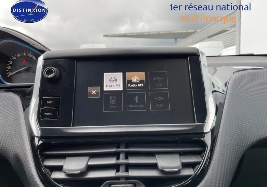 Écran tactile central du tableau de bord d'une Peugeot 2008 blanc nacré, avec commandes radio FM et AM visibles.