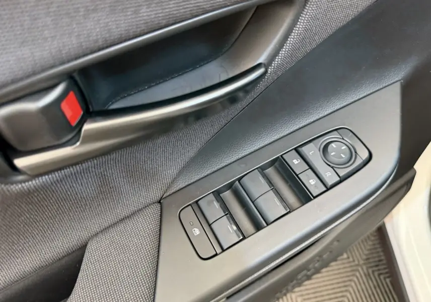 Détail des commandes de lève-vitres et rétroviseurs sur la porte avant gauche d'un Toyota C-HR blanc 2024.