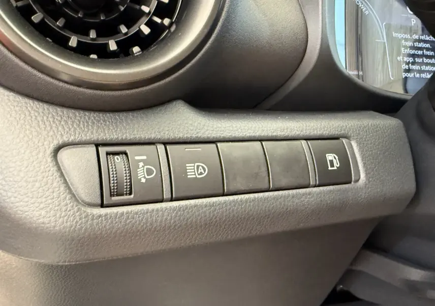 Vue rapprochée des commandes côté gauche du tableau de bord du Toyota C-HR blanc 2024, boutons d'éclairage et carburant visibles.