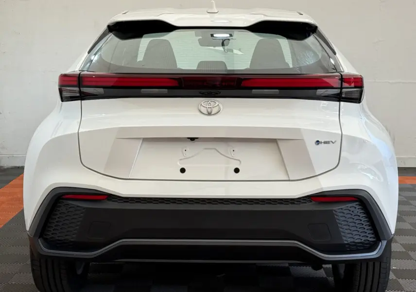 Vue arrière du Toyota C-HR blanc 2024 avec feux LED horizontaux et logo hybride HEV visible sur le coffre.
