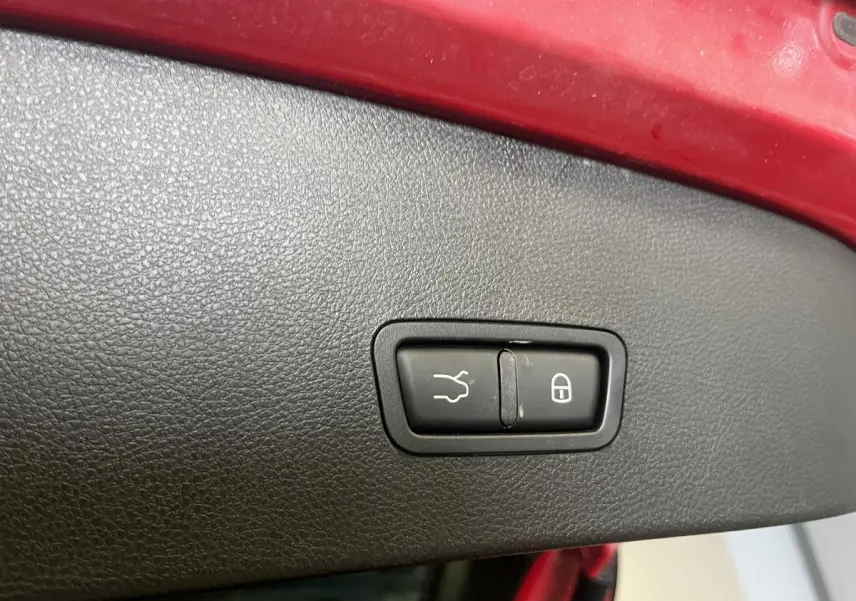 Boutons d'ouverture de coffre et de verrouillage intégrés dans le hayon rouge de l'Alfa Romeo Tonale 2024.