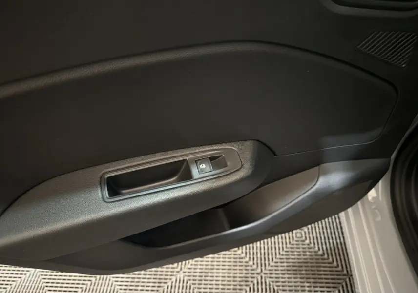 Gros plan sur la poignée intérieure côté droit de la porte d'une Renault Clio gris clair, avec bouton de verrouillage intégré.