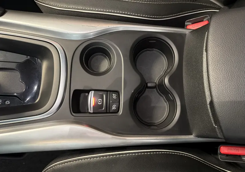 Vue plongeante sur la console centrale noire du Renault Kadjar gris, avec porte-gobelets et bouton de frein à main électronique allumé.