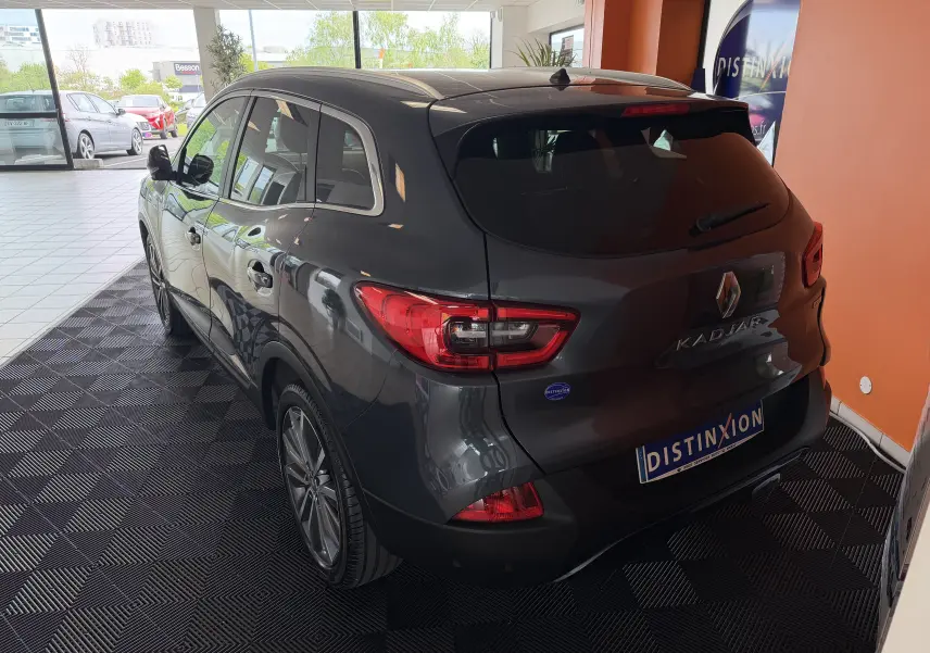 Vue 3/4 arrière droite d'un Renault Kadjar gris 2016 dans un showroom, avec feux arrière LED et jantes alliage.