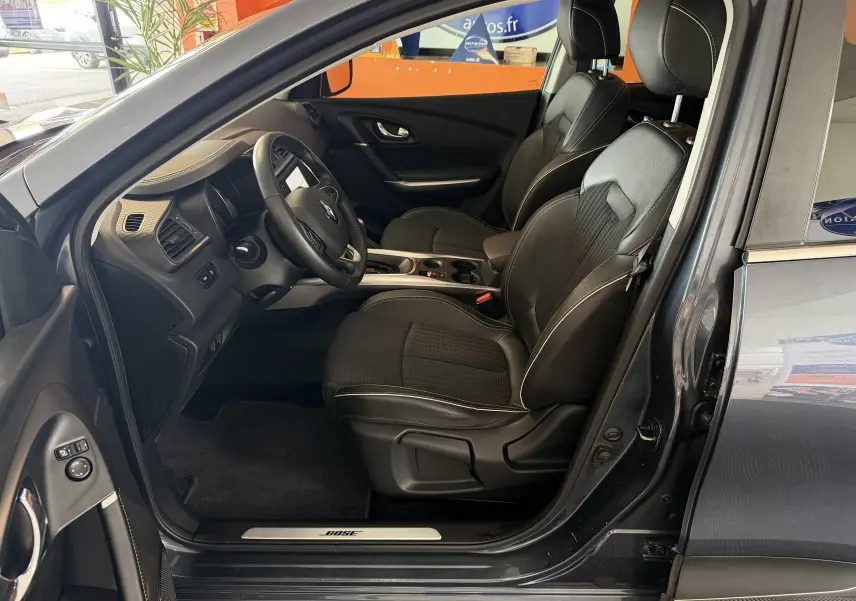 Vue intérieure côté conducteur du Renault Kadjar gris 2016, mettant en valeur les sièges noirs et le volant multifonction.