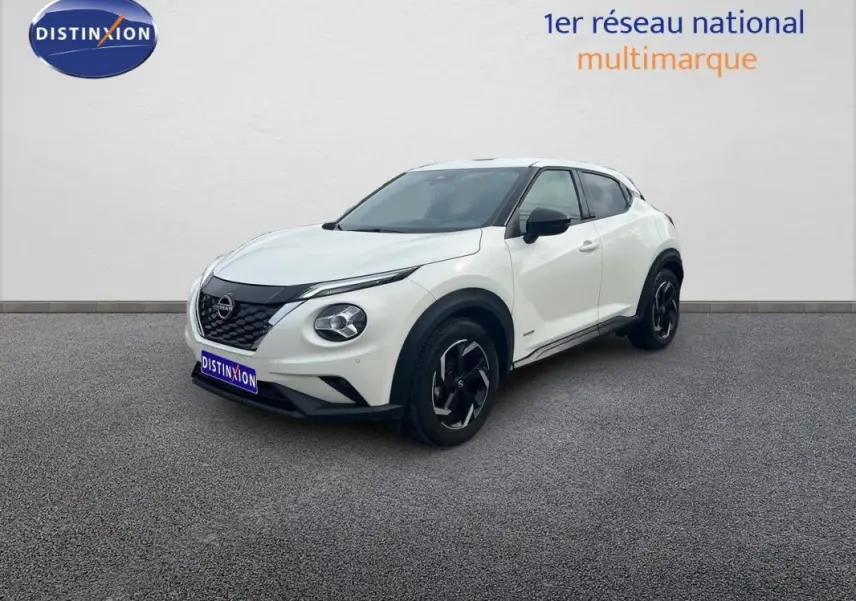 Nissan Juke blanc en 3/4 avant droit, avec jantes aluminium noires et calandre noire distinctive.
