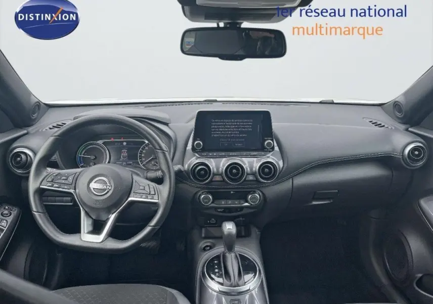 Vue intérieure frontale du tableau de bord noir du Nissan Juke 2024 avec écran tactile central et volant cuir multifonction.
