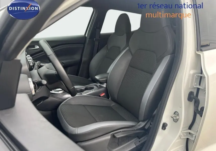 Vue intérieure côté conducteur du Nissan Juke blanc 2024, sièges noirs avec surpiqûres grises et volant cuir.