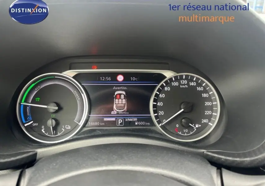 Vue rapprochée du tableau de bord du Nissan Juke blanc 2024, affichage numérique et compteurs analogiques visibles.