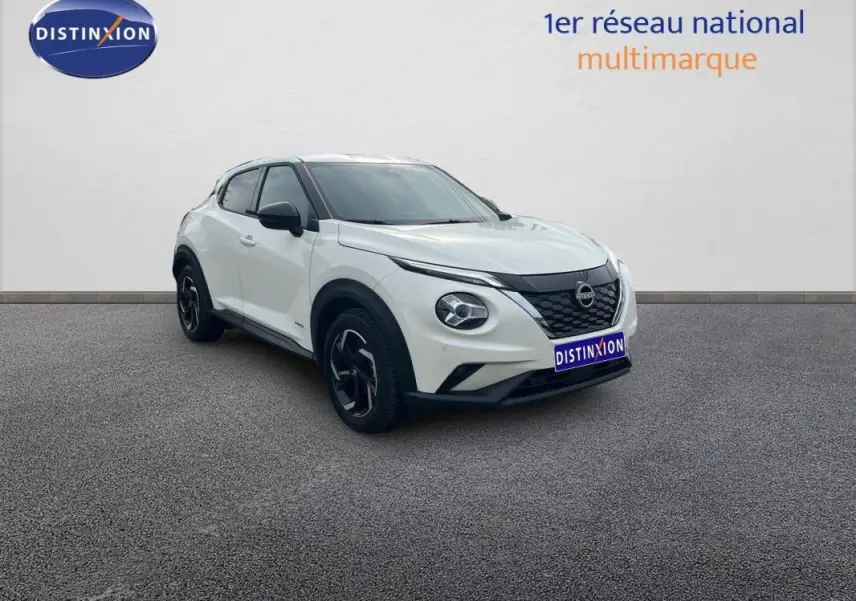 Nissan Juke blanc en 3/4 avant droit, avec calandre noire et jantes aluminium distinctives.