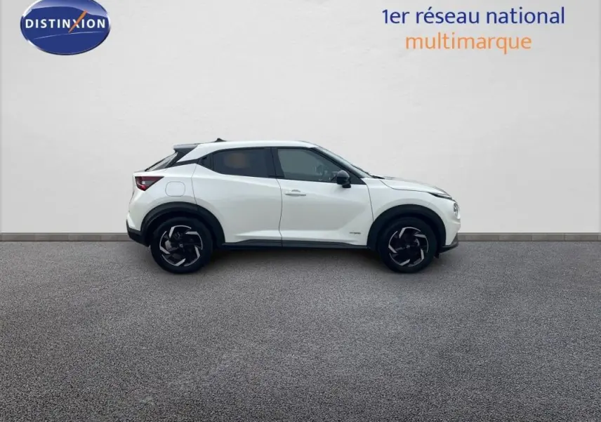 Vue de profil côté gauche du Nissan Juke blanc 2024 hybride avec jantes aluminium et toit noir.