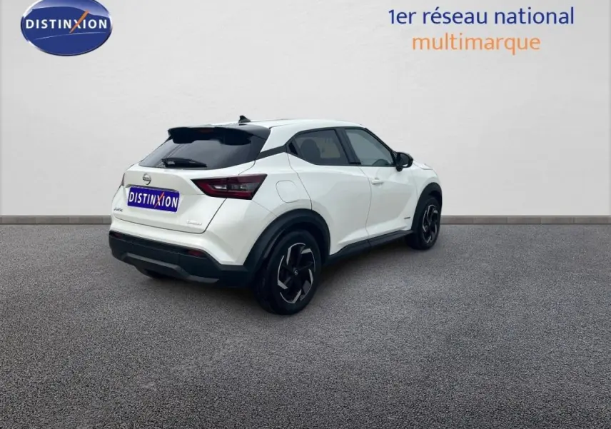 Vue 3/4 arrière droite d'un Nissan Juke blanc 2024 avec jantes aluminium et vitres teintées.
