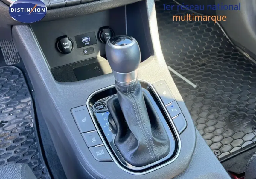 Gros plan sur la console centrale de la Hyundai i30 SW 2023, montrant le levier de vitesse automatique et les commandes de confort.