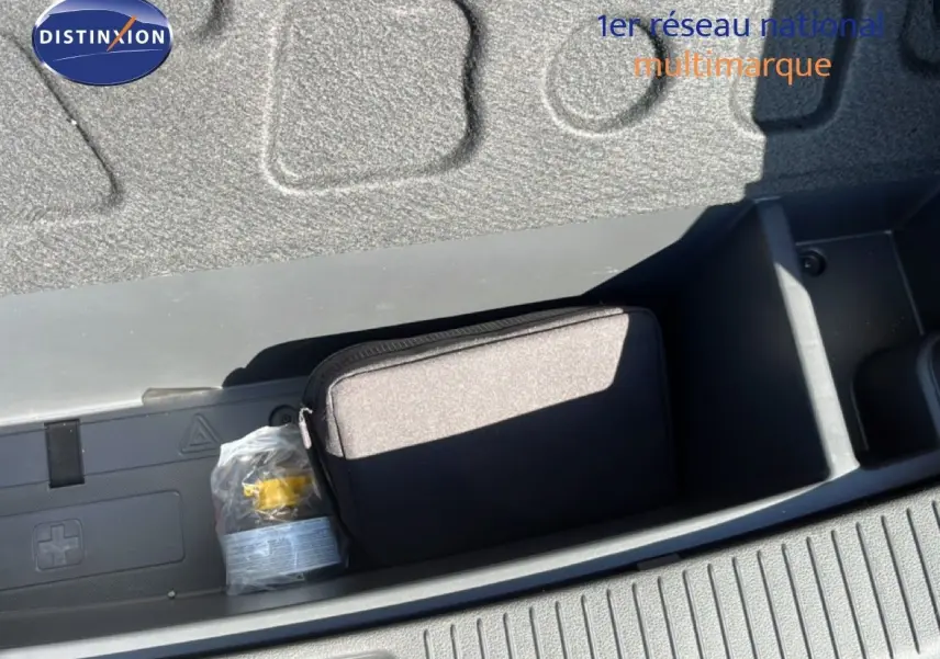 Coffre ouvert de la Hyundai i30 SW 2023 en Sunset Red Metal, montrant un rangement avec trousse et équipement de sécurité.