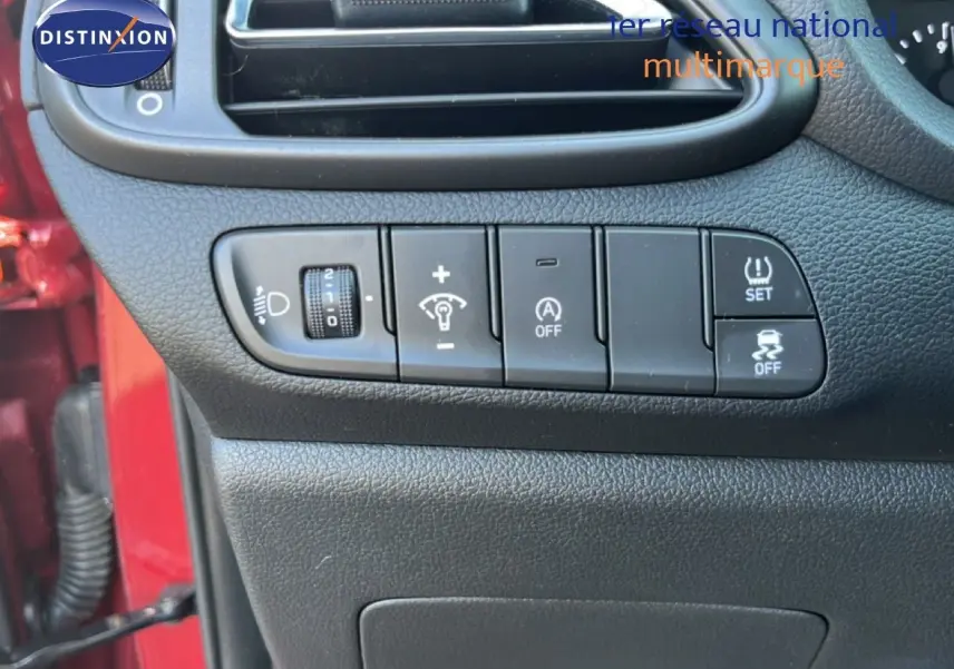 Vue rapprochée du tableau de bord côté gauche avec commandes d’éclairage et aides à la conduite sur Hyundai i30 SW rouge.