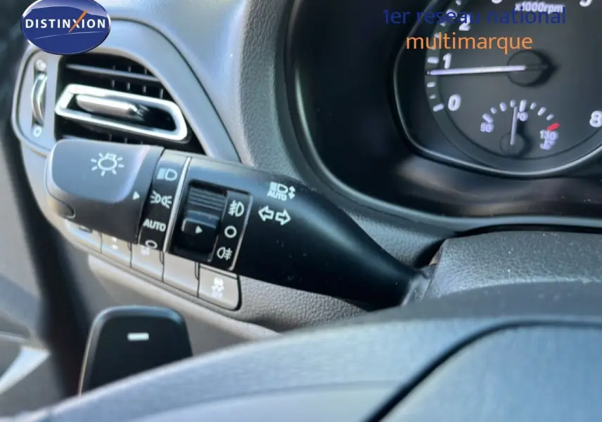 Gros plan sur la commande des feux et clignotants côté gauche du tableau de bord d’une Hyundai i30 SW rouge.