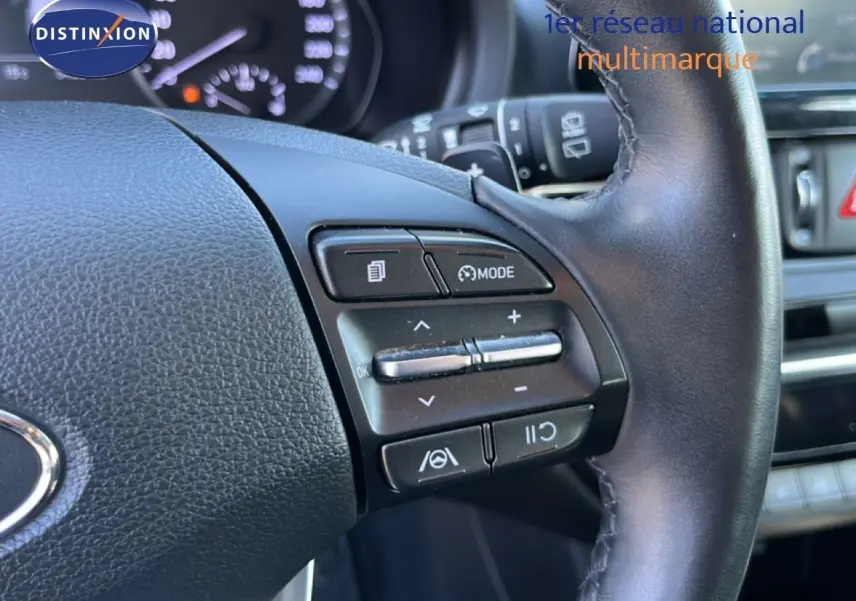Gros plan sur les commandes au volant à droite du Hyundai i30 SW 2023, intérieur noir avec tableau de bord en arrière-plan.