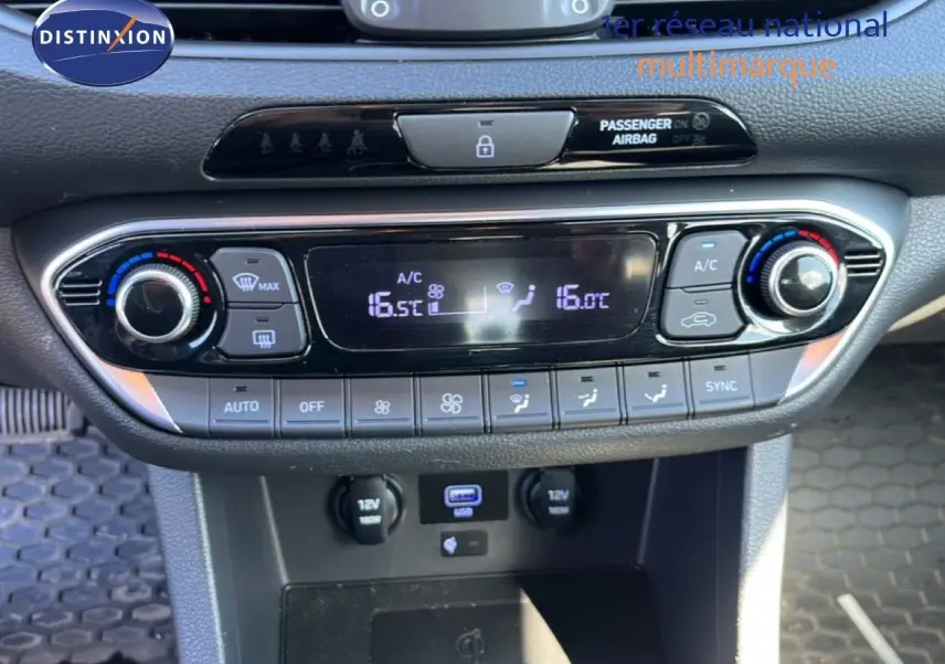 Vue rapprochée de la console centrale de la Hyundai i30 SW 2023, avec commandes climatisation digitale et ports USB et 12V.