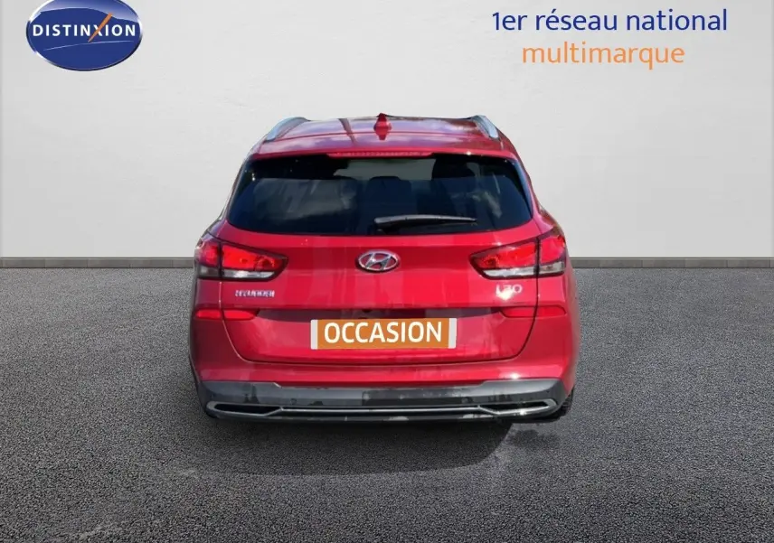 Vue arrière d'une Hyundai i30 SW 2023 rouge Sunset Red Metal avec feux LED et badge i30 visible.